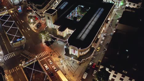 Farmers-Market-in-Funchal-at-night-with-streets-decorated-with-Christmas-lights,-aerial