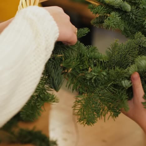 woman and baby make christmas wreath from conifers