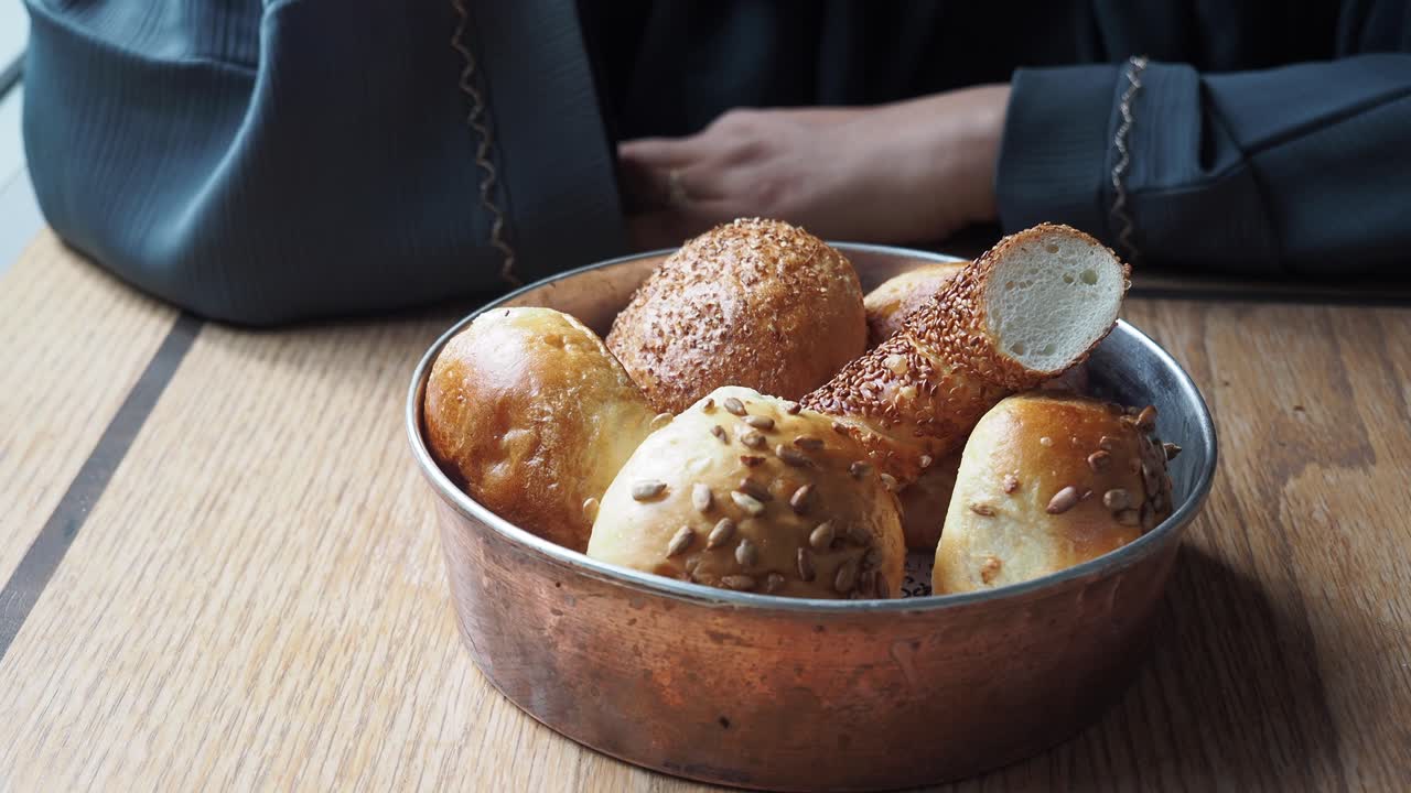 primer plano de la mano de la mujer alcanzando un simit, un pan turco cubierto de semillas de sésamo