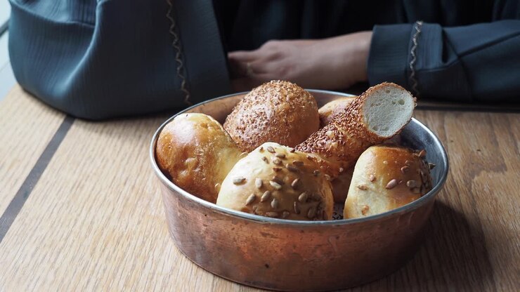 Close-up of woman's hand reaching for a simit, a turkish bread covered in sesame seeds