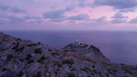 Side-panning-shot-of-famous-lighthouse-Faro-de-Formentor-Mallorca-during-sunrise,-aerial