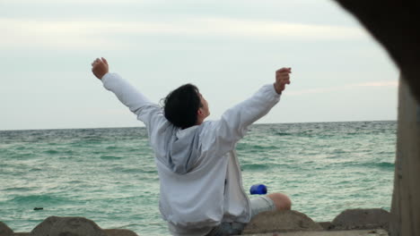 young modern guy yawn while sitting resting on beach , zooming out view form a tunnel canal