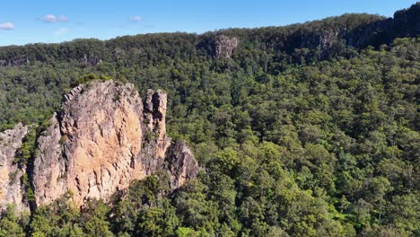 drone footage captures the iconic nimbin rocks surrounded by dense greenery under clear blue skies