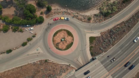 bird's eye aerial view of three super cars parked in a roundabout on the edge of okanagan lake kelowna bc with camera ascending slowly rotating