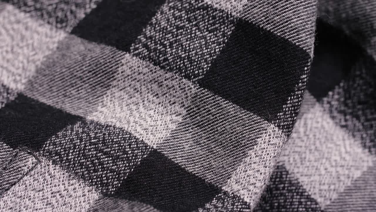 A black and white plaid flannel shirt with a glossy button and soft folds during a slow macro pan
