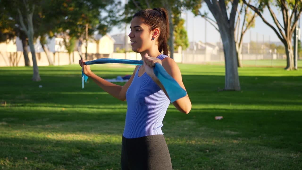 A young woman training her muscles with resistance bands in an injury rehab workout in the park