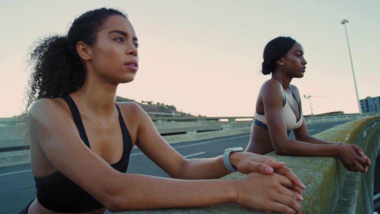 Two Fit Women Resting After Workout on Urban Bridge