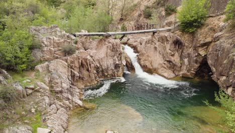 video de drone volando sobre puente de madera cascada río montaña bosque monte paiko
