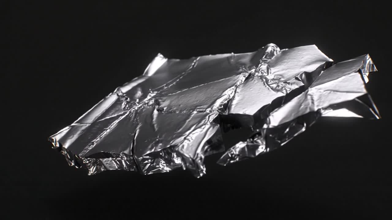 Sequence starting foil sheet rotating and flattening in studio, showing right folded fragment