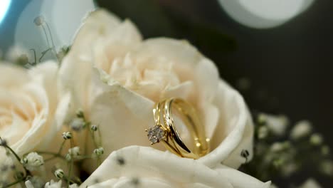 bouquet of white roses with shiny wedding rings between their petals