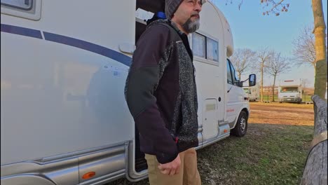 a man wearing a knitted hat gets out of his motorhome