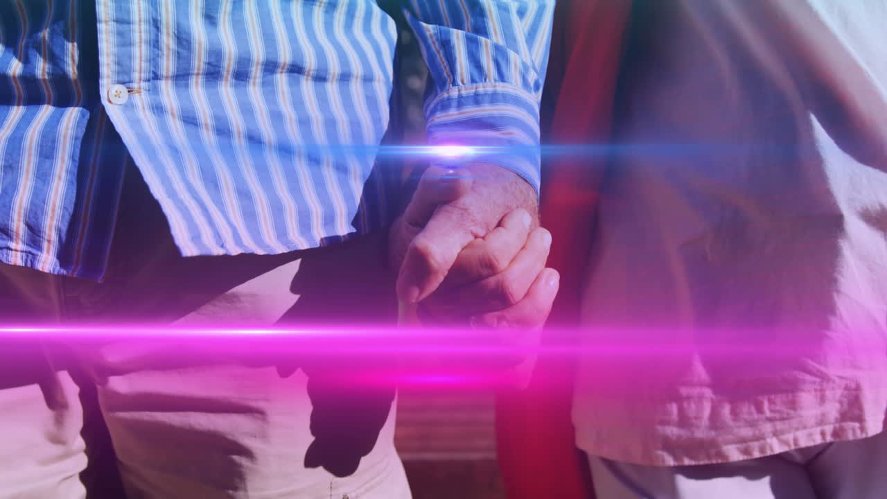 손을 잡고 공원에서  ⁇ 고 있는 노인 부부의 중간 부분을 가로질러 움직이는 빛의 애니메이션