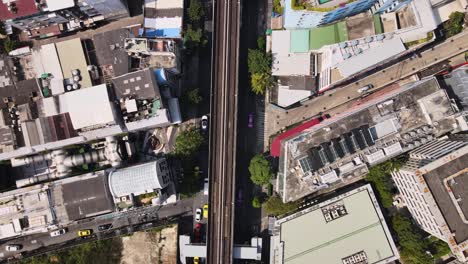 4k-Move-along-the-BTS-railway,-Aerial-Cinematic-shot-above-BTS-Railway-among-skyscrapers-in-Bangkok-City