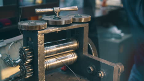 jeweler processes silver wire with tool at workplace closeup