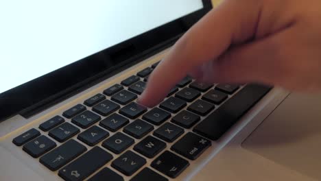 single male right hand typing on laptop keyboard, medium close-up