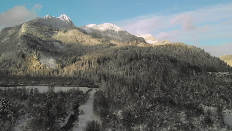 descending aerial drone flight showing snowy mountains in the tirolean alps, the river lech and a wooden bird watchtower