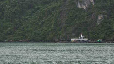 A-view-of-Ha-Long-Bay-in-Vietnam,-with-the-water-visible-in-the-foreground-and-a-mountainous-island-in-the-background