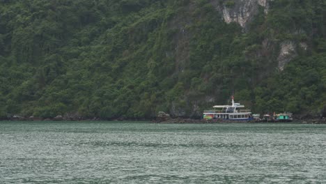 a view of ha long bay in vietnam, with the water visible in the foreground and a mountainous island in the background