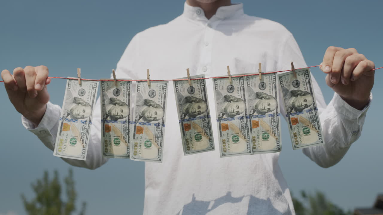 한 남자가 지폐가 매달린 옷줄을 들고 있습니다. 바람이 지폐를 흔들고 있습니다. - 불법 수입 개념