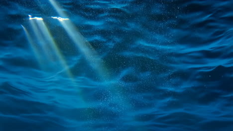 sunlight filtering through deep blue water with bubbles