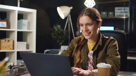smiling business woman typing online after work in late night hipster office.