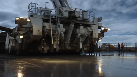 massive industrial machine and workers on wet ground