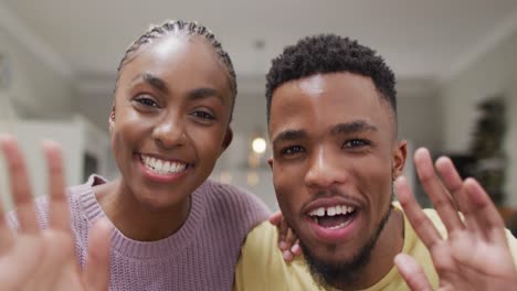 happy african american couple waving to camera during video call