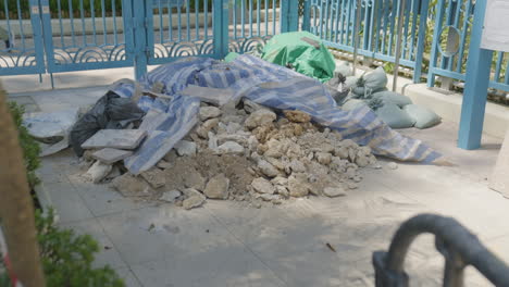 pile of rubble and dirt left on streetside covered by blue white tarp, hong kong