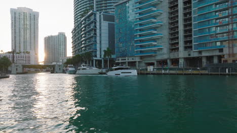 Bajo-Vuelo-Sobre-Aguas-Turquesas-Cristalinas-En-El-Río-Que-Fluye-A-Través-De-La-Ciudad.-Barco-Pasando-Por-El-Paseo-Marítimo.-Miami,-Estados-Unidos