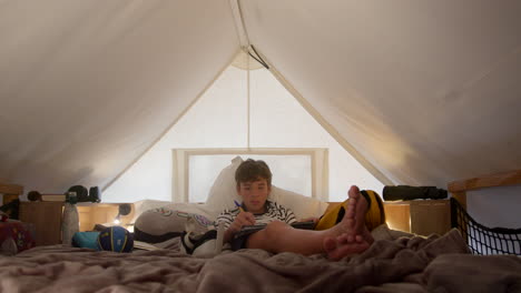 teenage boy writing in bed in a cozy room