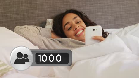 mujer acostada en la cama sonriendo mientras envía mensajes de texto en su teléfono 4k