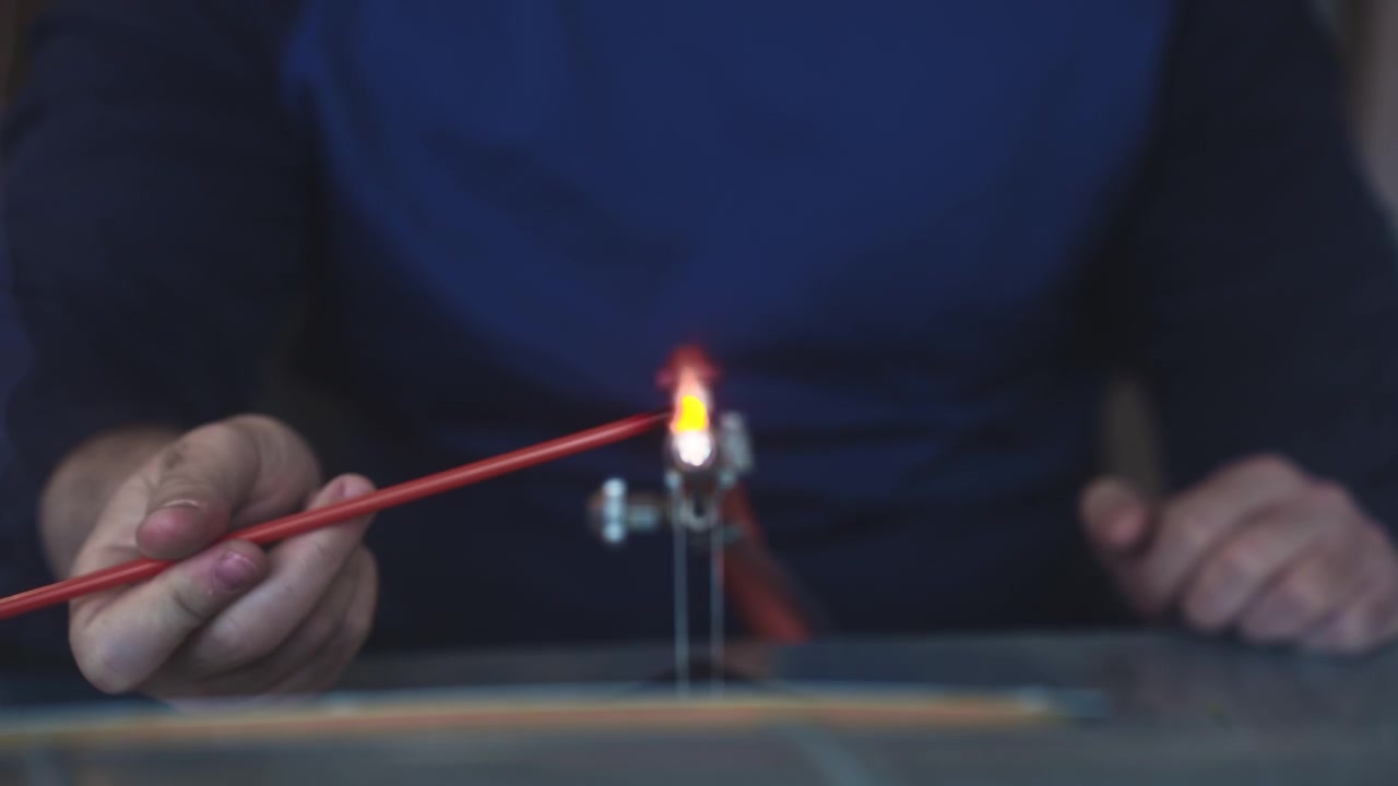 tourist participating in a traditional Viking jewelry glass-making workshop in Lofoten Islands, Norway. Hands melting glass beads with a torch burner in a local artisan studio