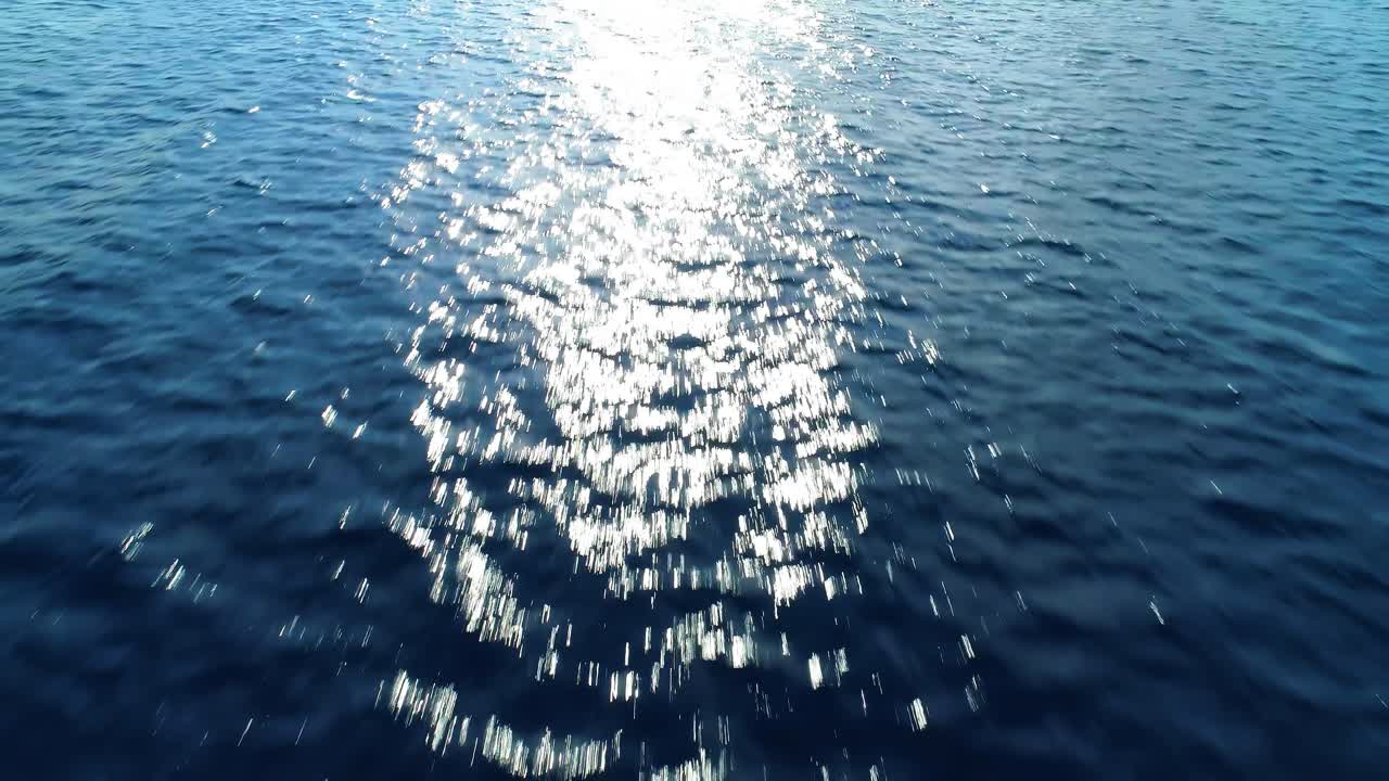 해가 지는 곳으로 향하는 공중 도리, 카리브해 푸른 바다 질감을 가로질러 빛나는 반이는 빛