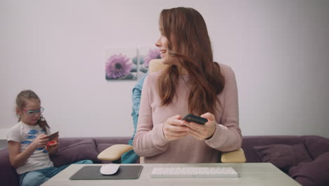 Happy-mother-talking-phone-at-home-workplace.-Busy-mom-at-home-office