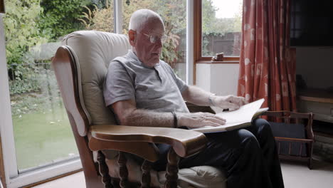 elderly man reading a book in a rocking chair
