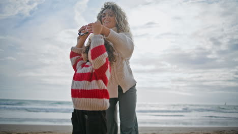 un niño lindo jugando a la cometa con su madre en la playa. un padre cariñoso enseñando ayudando a su hijo