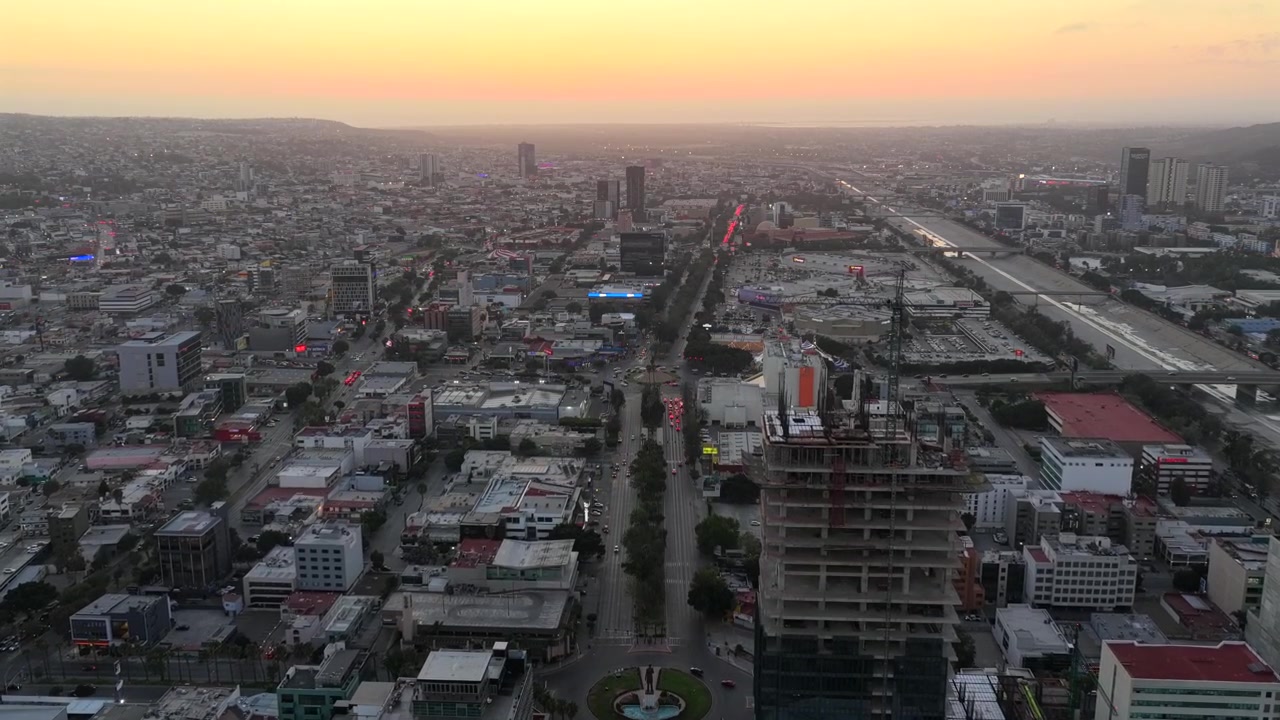 Paseo de los Héroes i centrum af Tijuana, Baja California, Mexico med udsigt over Monumento México og Monument til Kejser Cuauhtémoc rundkørslerne ved solnedgang. Luftfoto.
