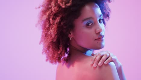 mujer biracial con cabello oscuro en luz azul y rosa, cámara lenta