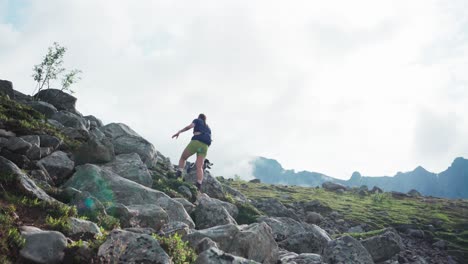 rear of a sporty woman climbing on the rocky mountain with a dog on a leash