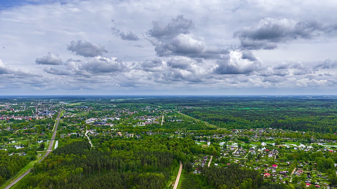 Cumulus clouds forming and flowing above countryside towns in rural Europe - high altitude aerial time lapse