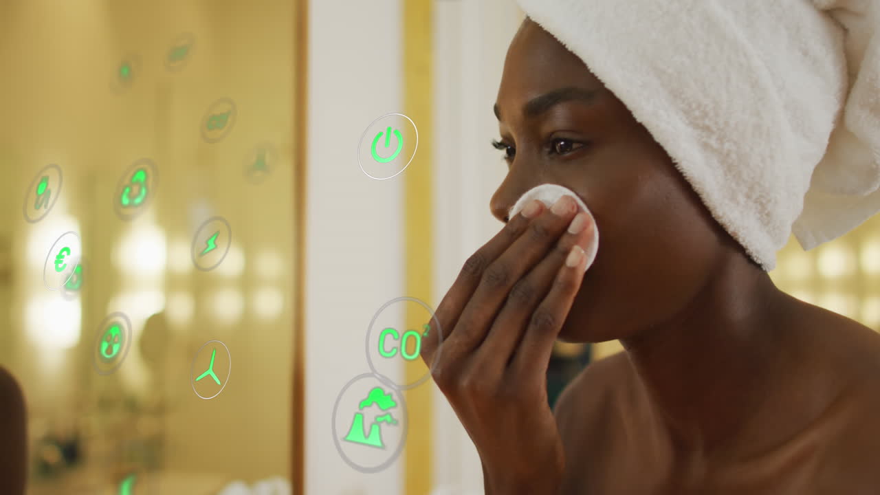 Animation of icons over african american woman cleansing face in bathroom
