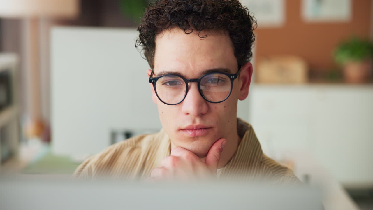 Young Man with Glasses Concentrating While Working on Computer