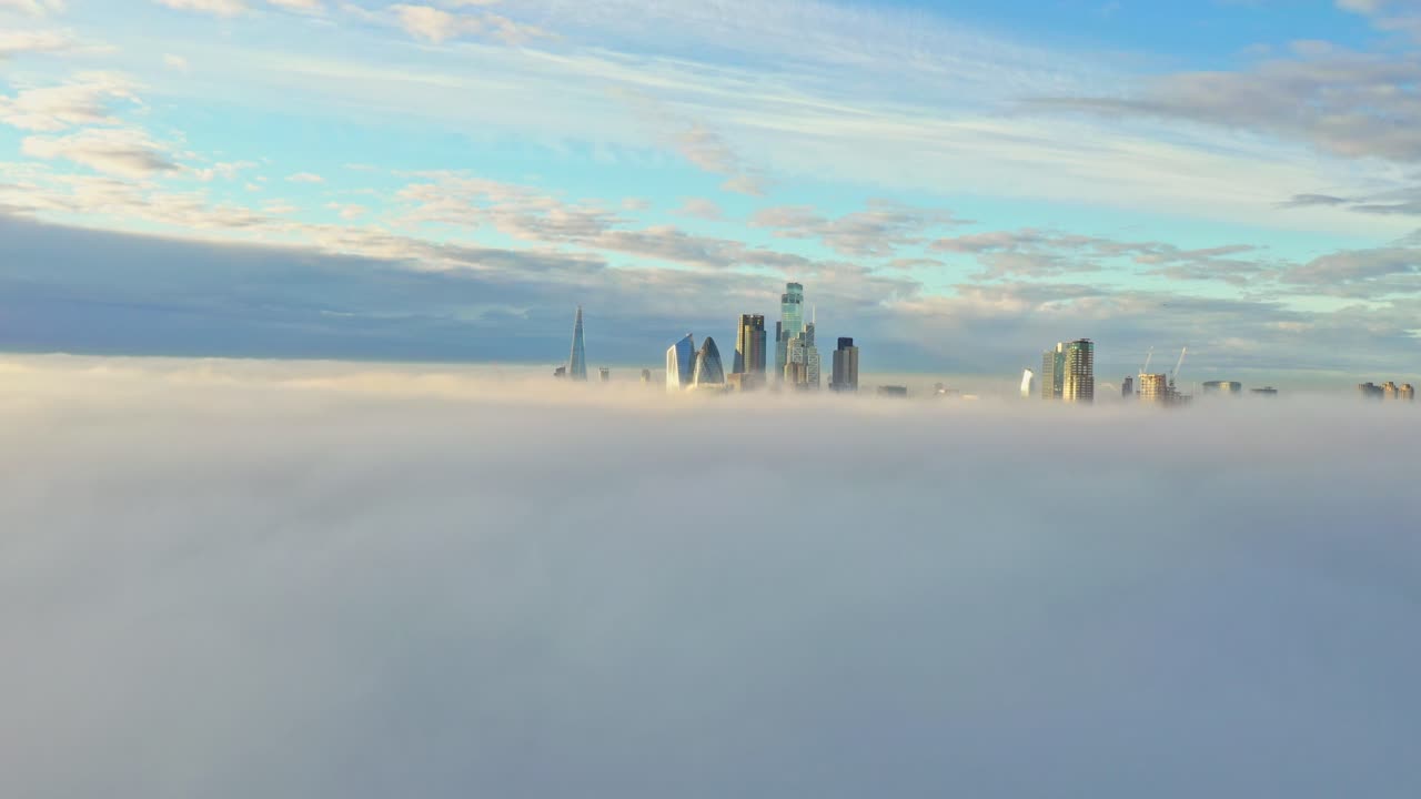 hiperlapso aéreo sobre la densa niebla nubosa hacia los rascacielos del centro de la ciudad de londres al amanecer.
