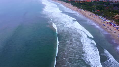 Foamy-Waves-Crashing-On-Sandy-Shore-Of-Kuta-Beach-In-Bali,-Indonesia---aerial-drone-shot