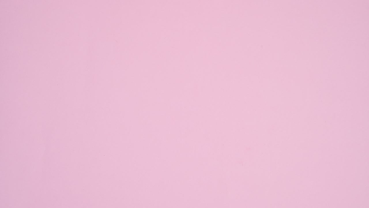 Sweets candies and lollipops appear under paper card note on pastel pink background. Stop motion flat lay