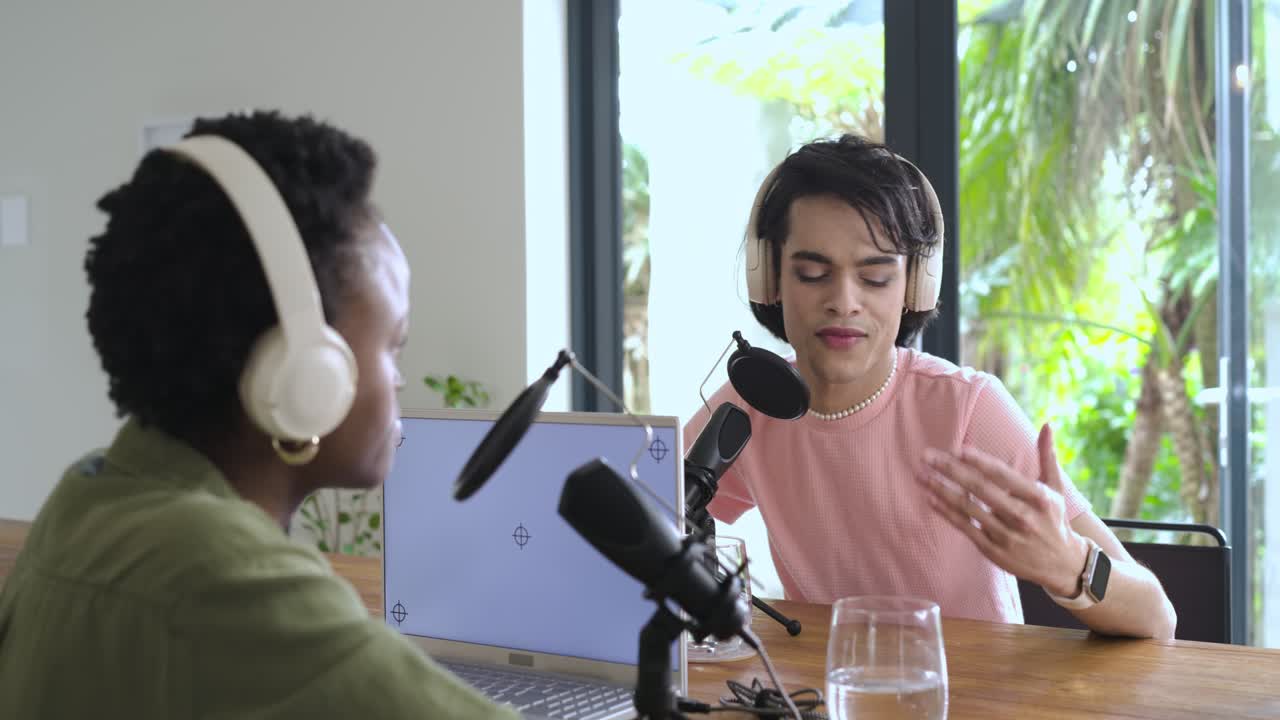 Colleghi diversi che registrano un podcast in studio con un uomo che gesticola verso il microfono e poi una donna che interviene
