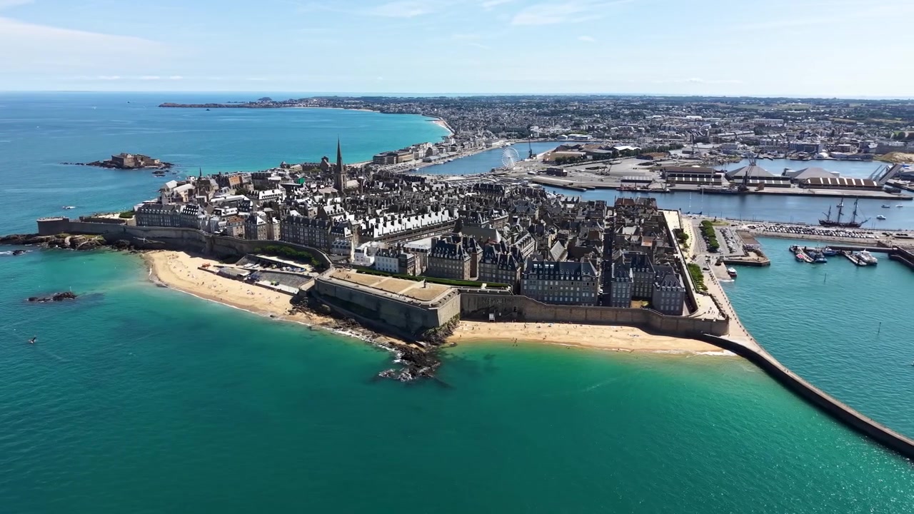 Tarihi surlarla çevrili Saint-Malo şehri etrafında yavaş bir sol yörünge çizerek, güçlendirilmiş surları, kumlu plajları, limanı ve turkuaz suları sergileyen sinematik drone çekimi.
