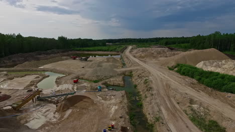 Cinematic-aerial-drone-revealing-the-landscape-and-activities-going-around-sand-and-stone-mining-area,-tracking-out-shot