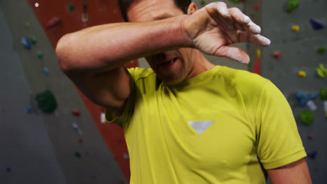 hombre empapando su mano con polvo de tiza antes de escalar la pared artificial 4k