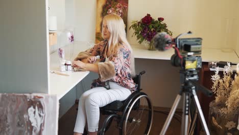 A-pretty-fair-haired-girl-in-a-wheelchair-paints-a-glass-vase